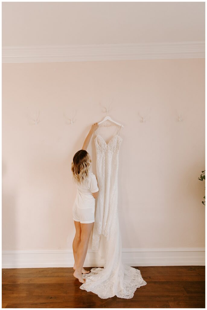Bride with wedding dress on hanger for wedding day packing list. 
