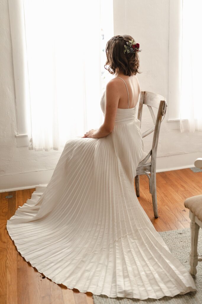 Bride looking out window in wedding dress.