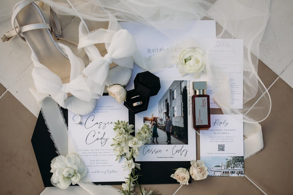 Black and white wedding invitations and shoes on the floor.