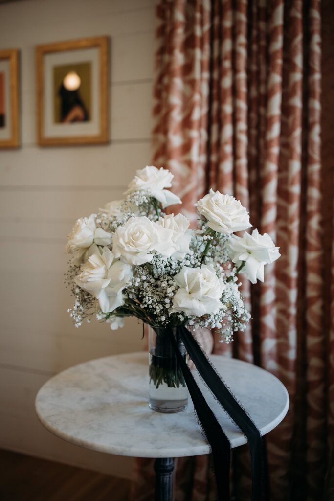 White roses in a vase on a table at a black and white wedding.