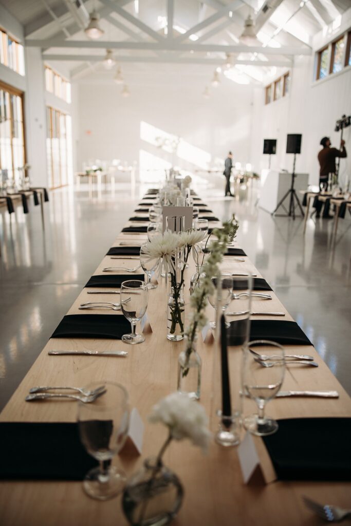 A black and white themed wedding reception is showcased with a wooden table.
