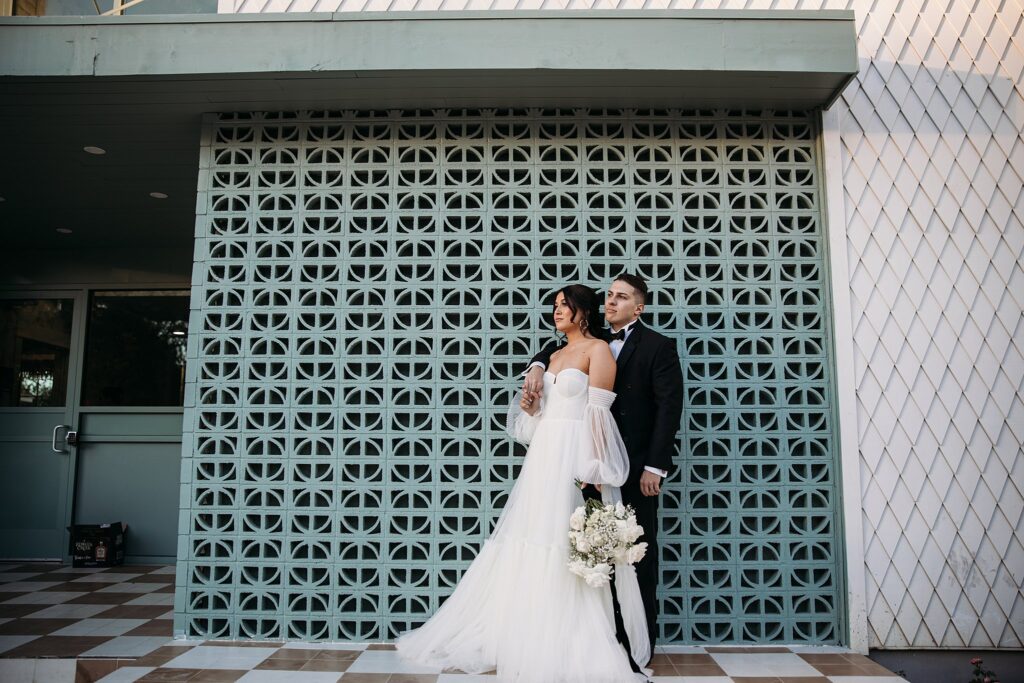 A black and white wedding - couple poses for a wedding photo in front of a building.