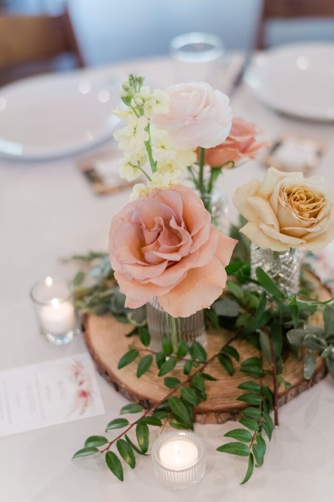 A rustic table adorned with Pecan Springs Ranch flowers and greenery on a wooden board.