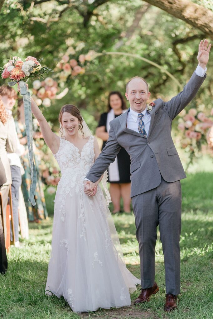A bride and groom of Pecan Springs Ranch walk down the outdoor wedding aisle.