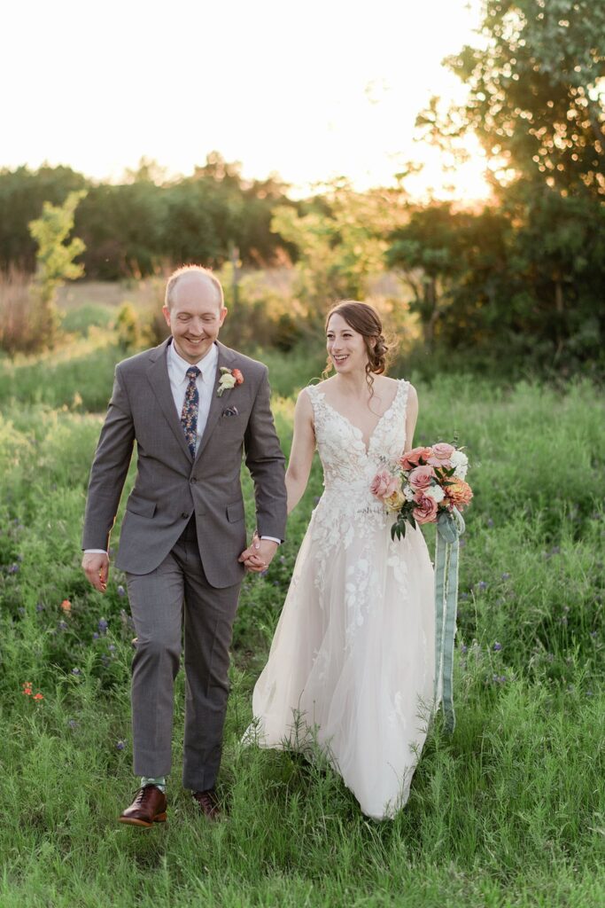 A bride and groom walking through the Pecan Springs Ranch at sunset.