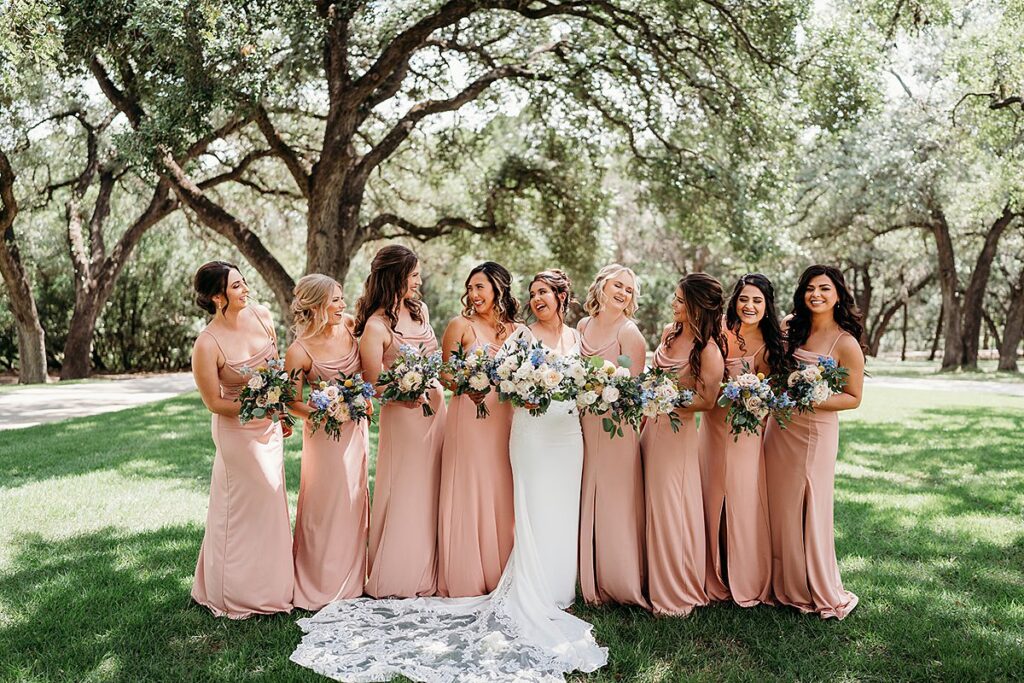 Bridesmaids in blush dresses pose for a photo.