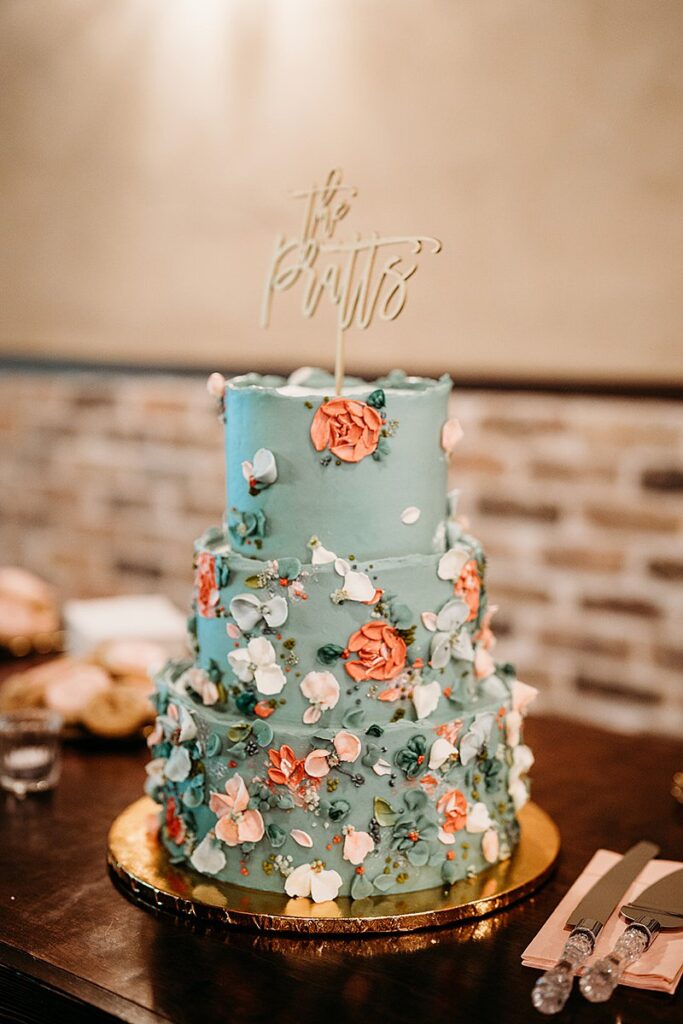 A blue wedding cake with flowers on top.