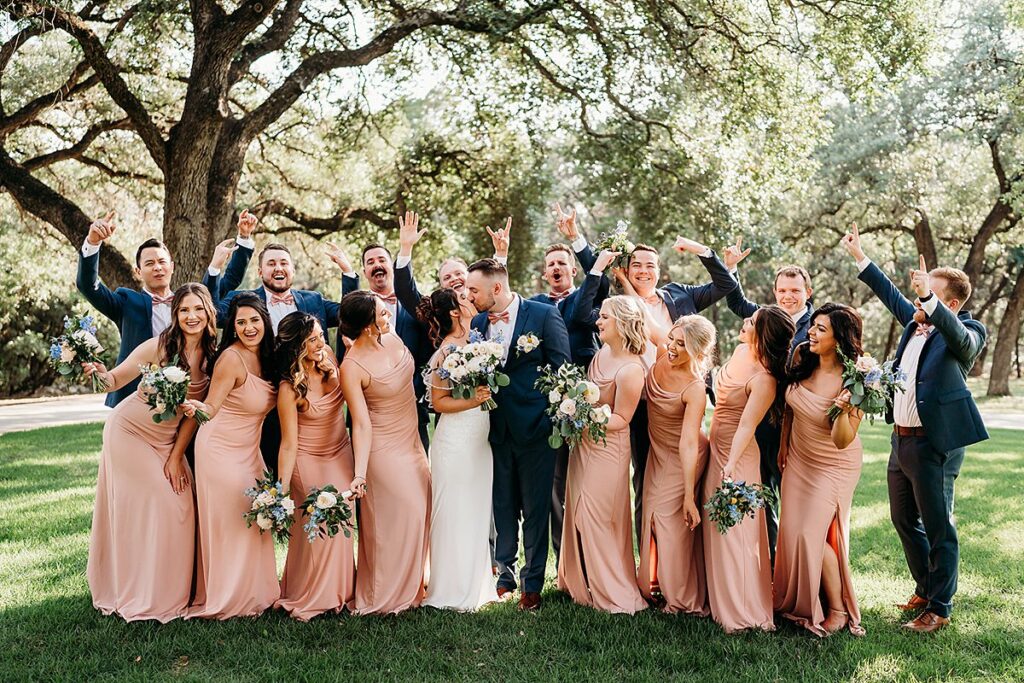 A group of bridesmaids and groomsmen pose for a photo at The Chandelier of Gruene.