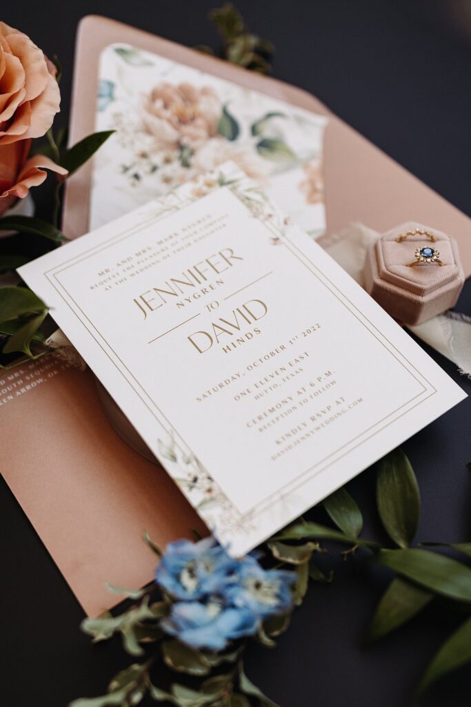 A wedding invitation with flowers and a ring.