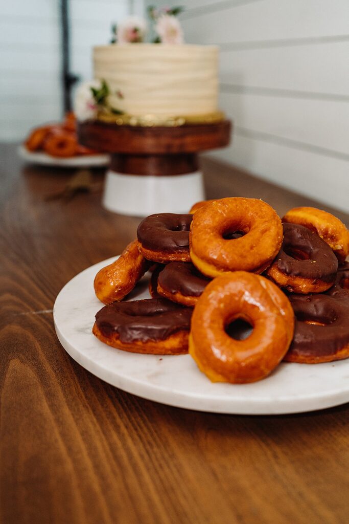 Donuts on a plate next to a cake.