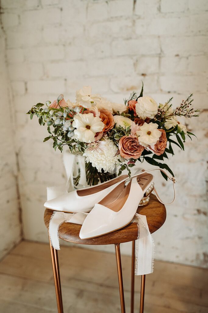 A pair of white wedding shoes on a wooden table.