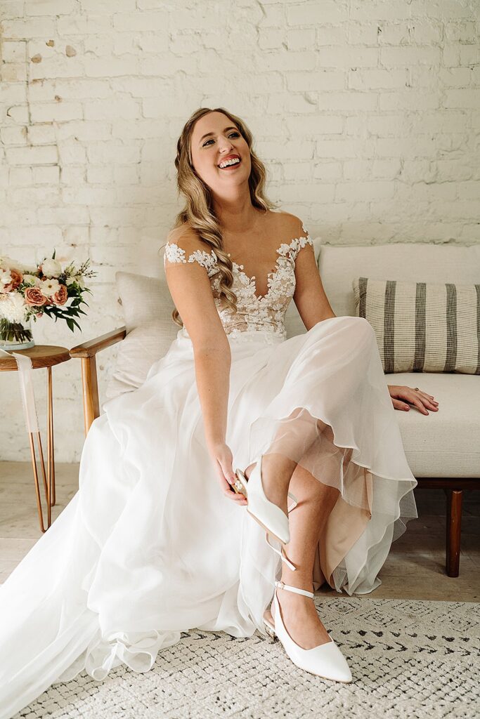 A bride sitting on a couch with her wedding shoes on.