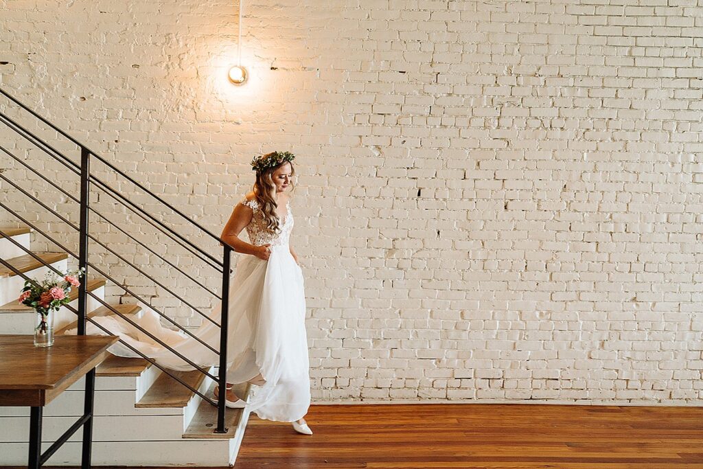 A bride standing on the stairs in a brick building.