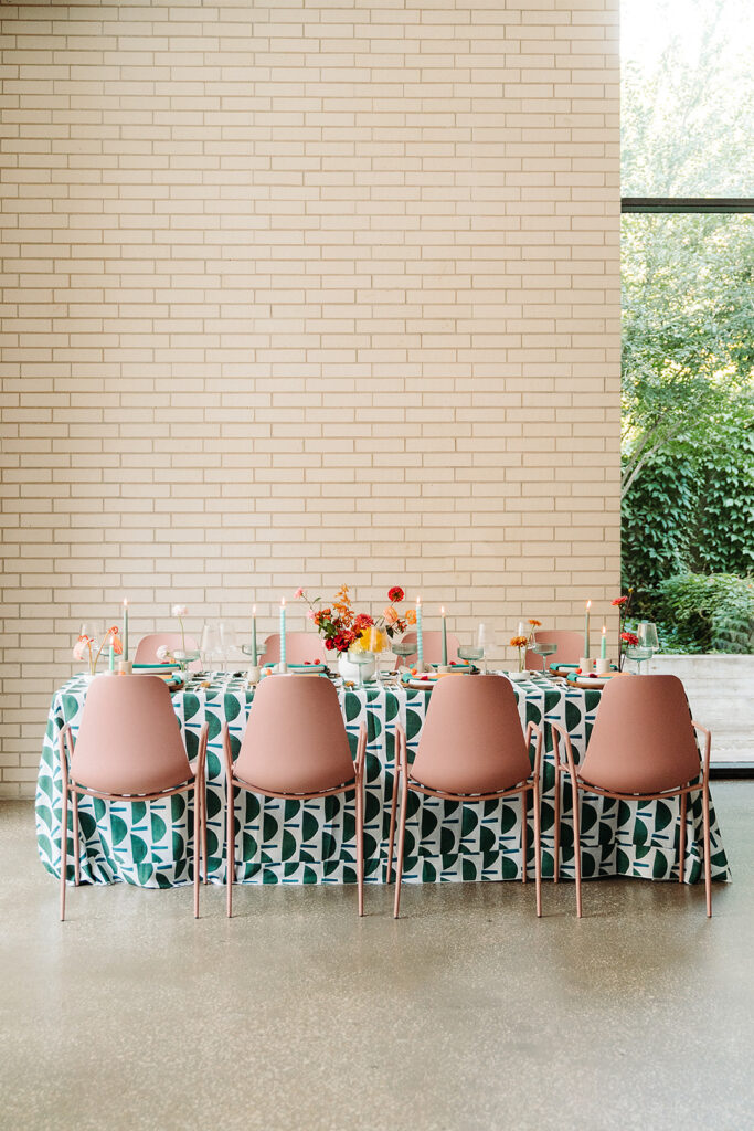 A South Congress Hotel wedding table set with pink chairs and a green tablecloth.