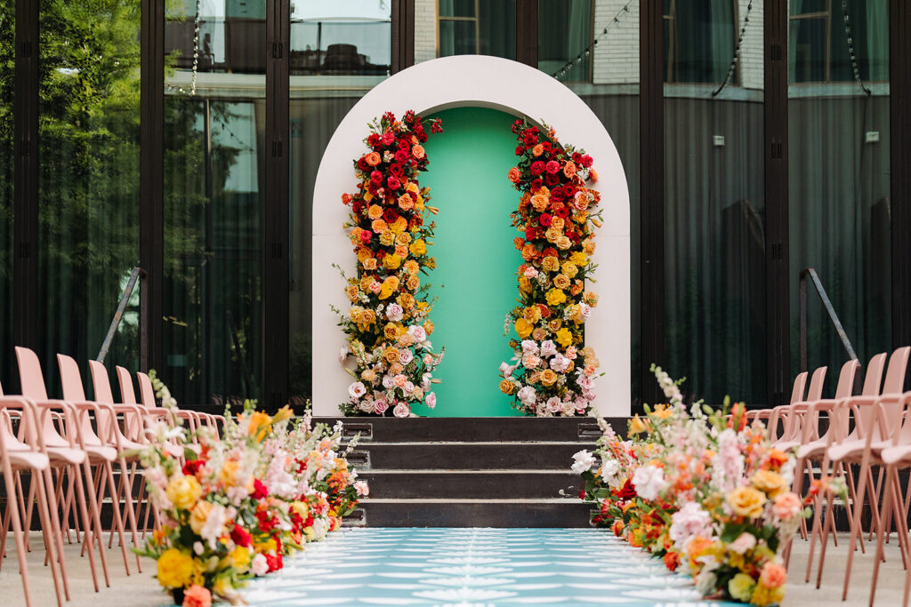 An outdoor South Congress Hotel wedding ceremony with colorful flowers and a blue door.