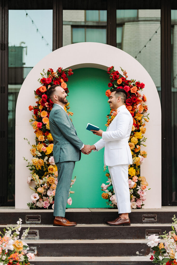 Two men standing in front of a colorful flower arch at South Congress Hotel. 