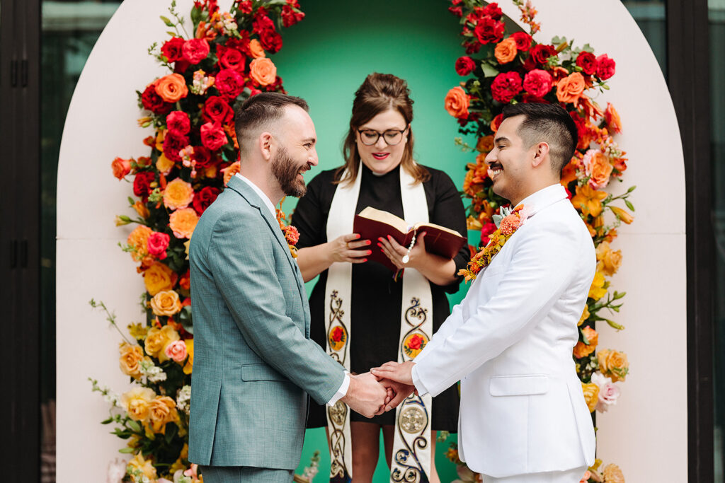 A groom exchange vows in front of a colorful South Congress Hotel wedding arch.