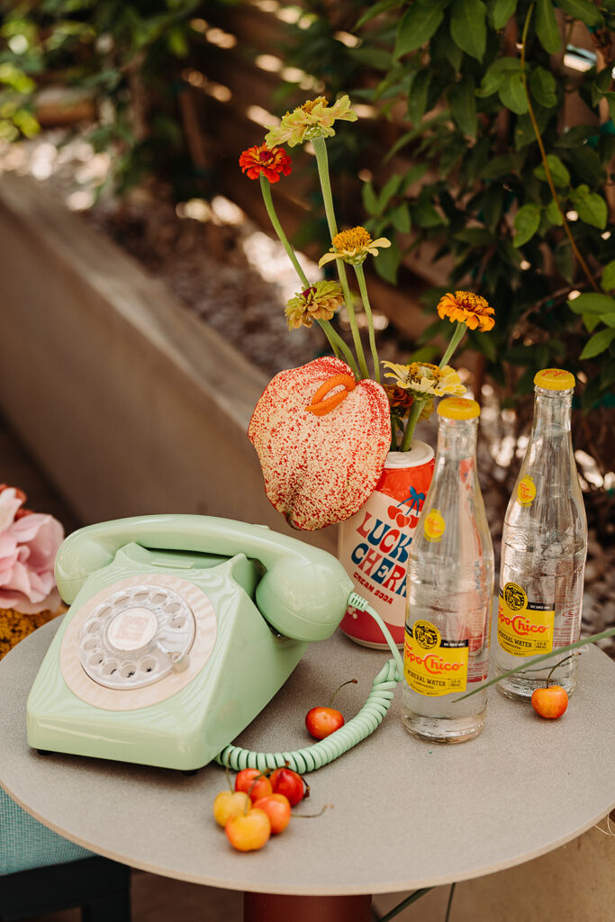 A green telephone sits on a table next to a bottle of water.