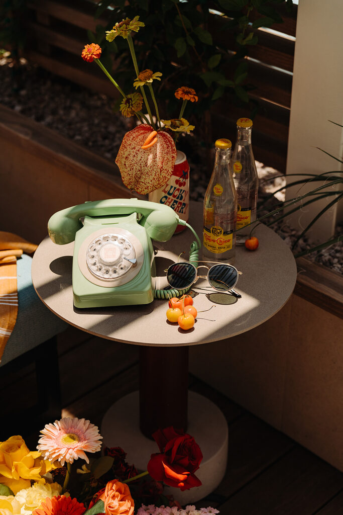 A green telephone sitting on a table next to flowers
