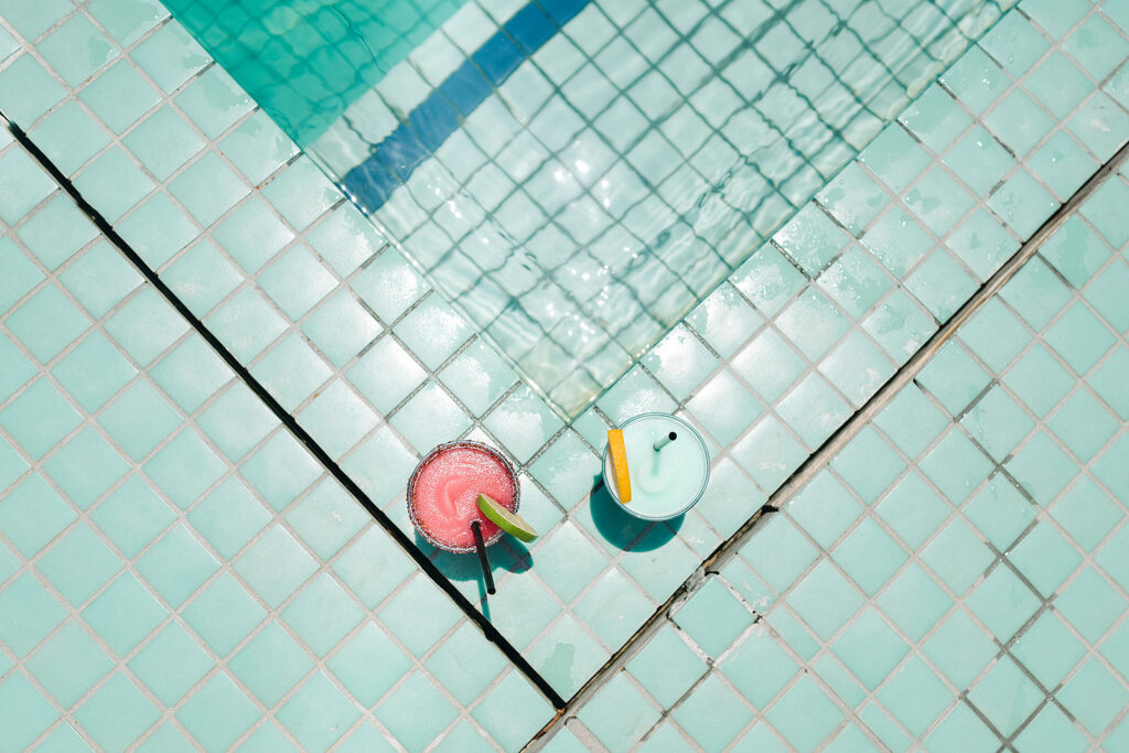 Two drinks sitting on top of a tiled pool