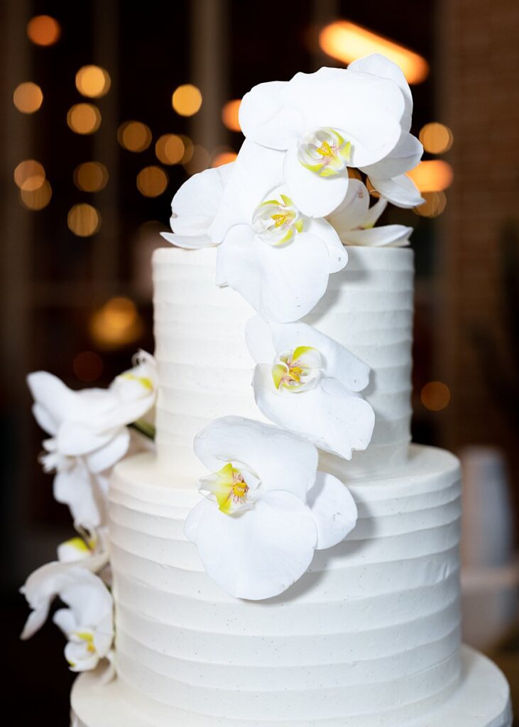 A white wedding cake with white orchids on top.