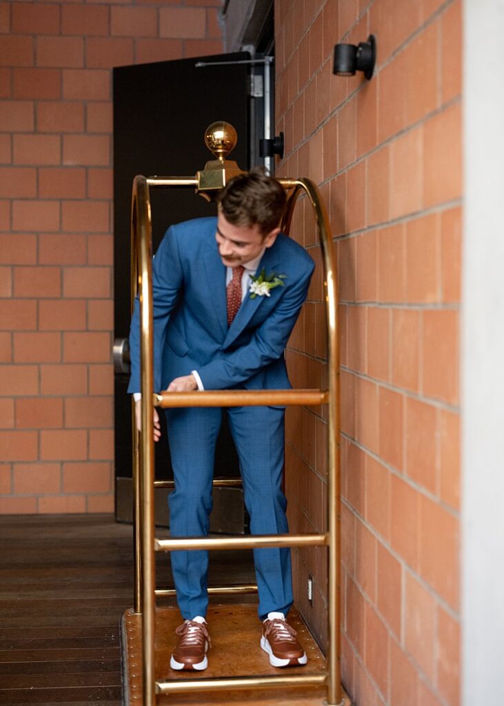 A man in a blue suit standing on an elevator at a hotel.