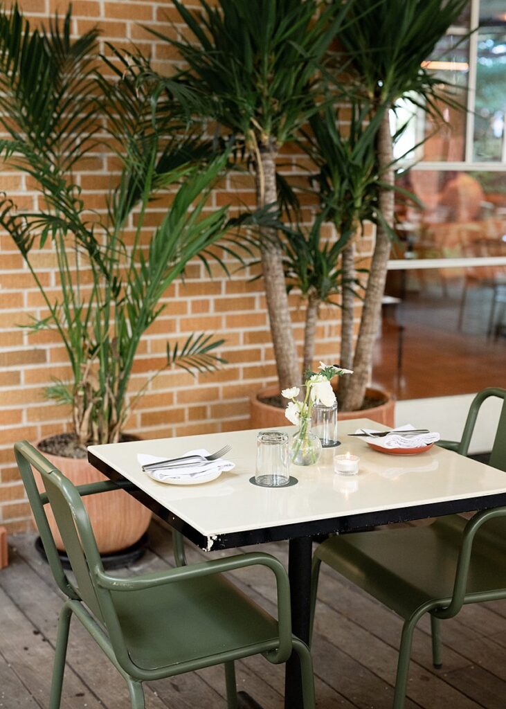 A Carpenter Hotel patio with a table and chairs adorned with a potted plant.