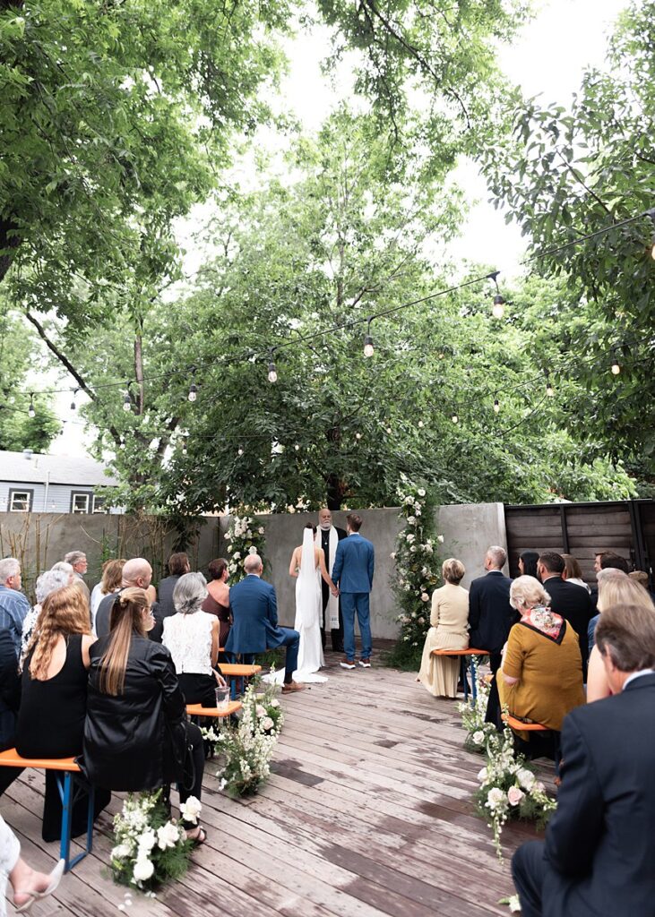 A Carpenter Hotel wedding ceremony on a wooden deck under a tree.