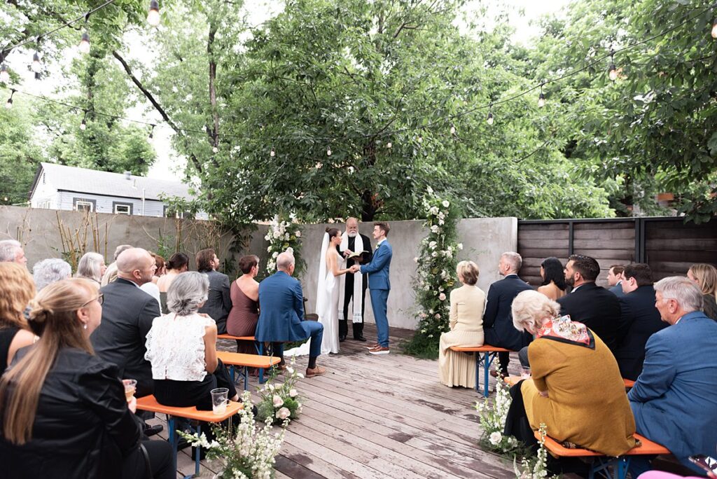 A Carpenter Hotel wedding ceremony in a backyard with a tree in the background.