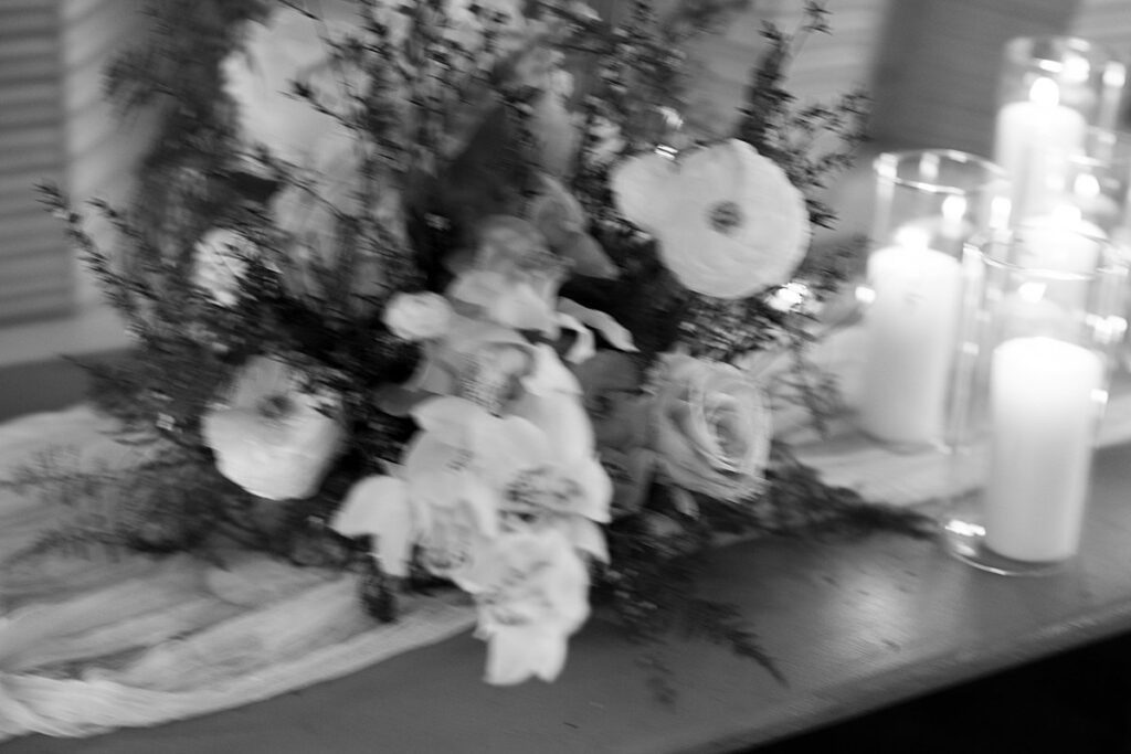 A black and white photo of a table with candles and flowers at a wedding.