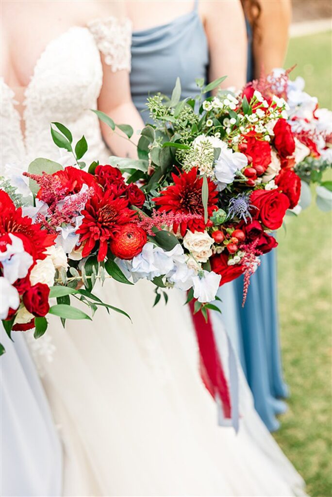 Bridesmaids holding red and white bouquets of flowers.