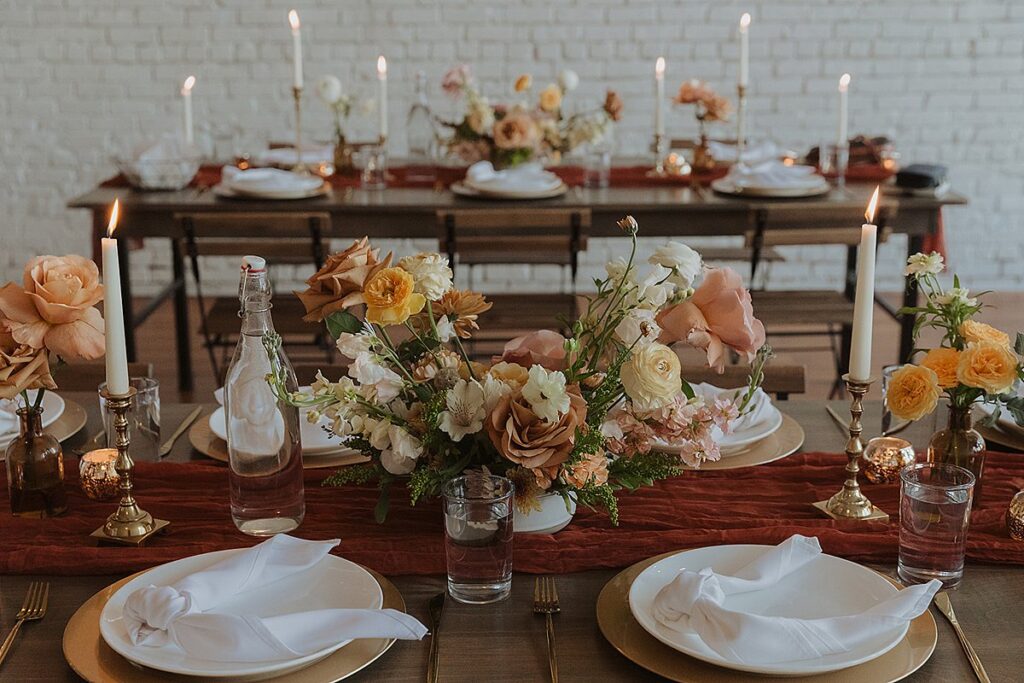 A table setting with candles and flowers on a wooden table.