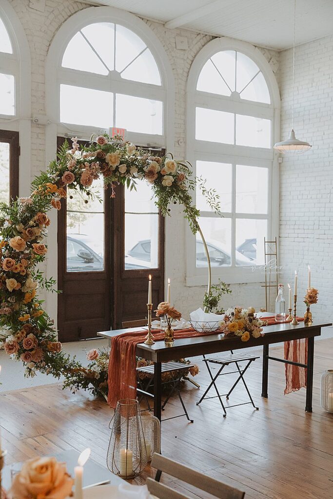 A floral arch with candles and flowers in the middle of a room at One Eleven East. 