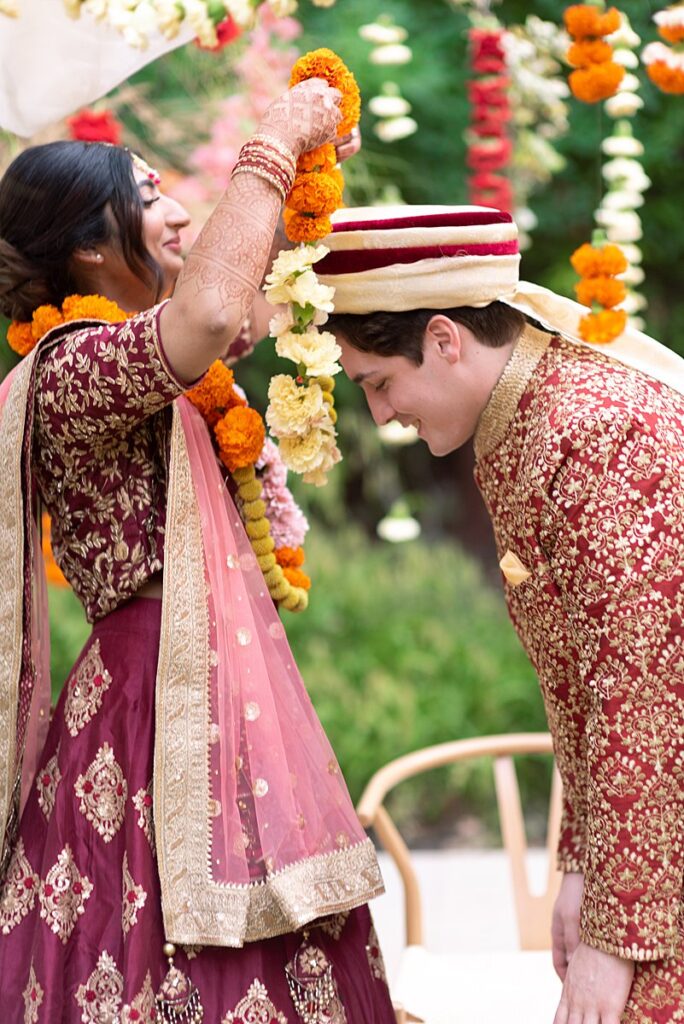 A bride and groom are putting on garlands during their Indian wedding ceremony at Hotel Magdalena.