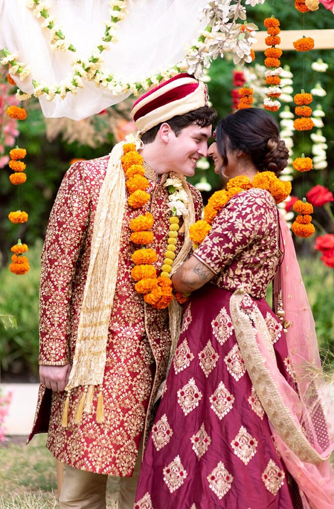 A bride and groom dressed in traditional Indian attire celebrating their wedding.