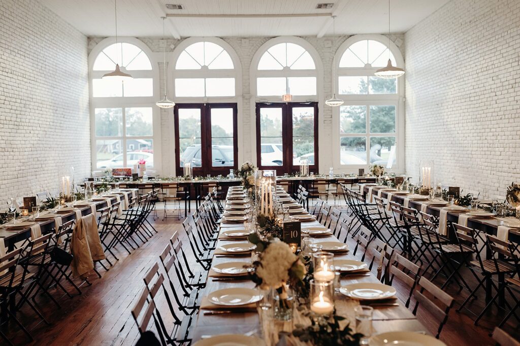 Elegant 111 East wedding dining setup in a bright room with arched windows and exposed white brick walls.