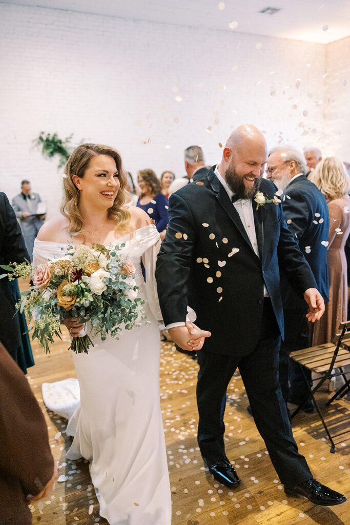 A couple exiting their ceremony at One Eleven East Wedding Venue.