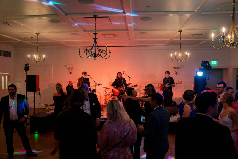 A live band performs on stage during a wedding reception, with guests enjoying the music and dancing. This moment captures one of the 2025 wedding trends: creating unforgettable entertainment experiences for guests.