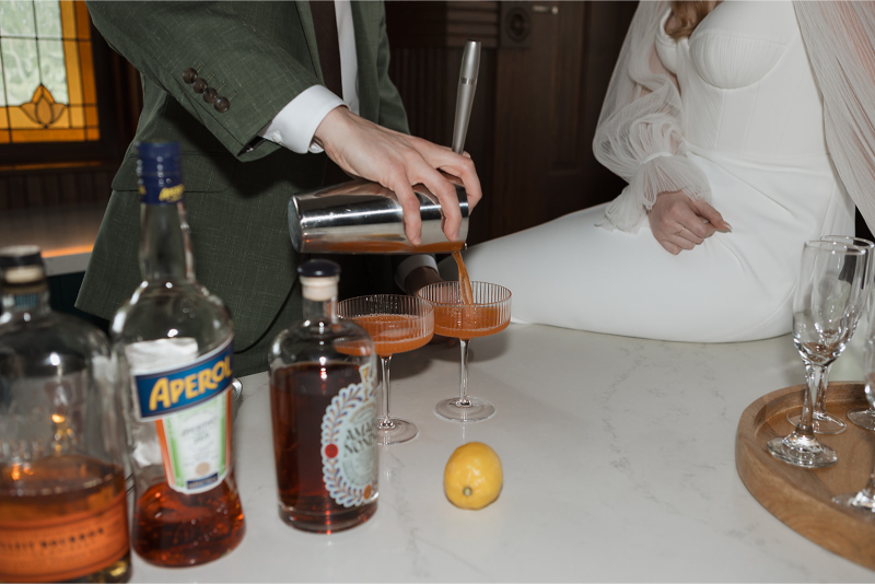 A bride and groom make cocktails together before their wedding ceremony. 