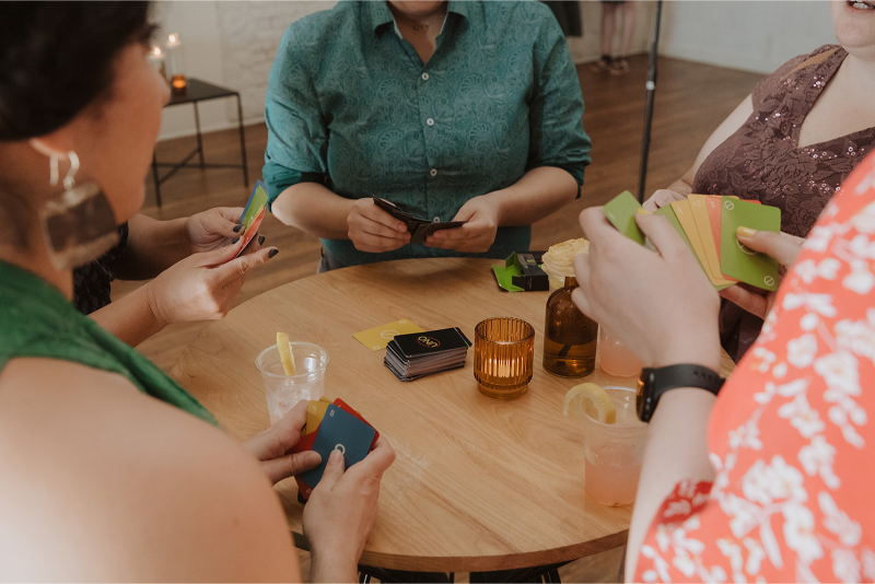 Wedding guests sitting around a wooden table playing UNO. 