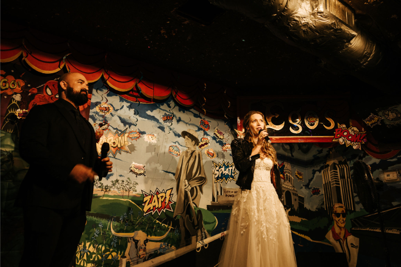 Bride and groom sing karaoke together during wedding afterparty. 