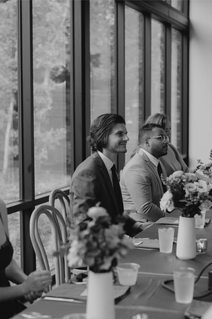 Groom smiles as he watches bride and her father share dance at their wedding. 