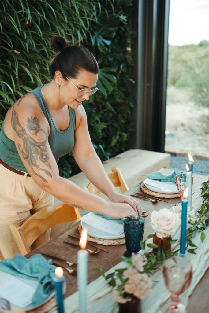 Sydney from In Ink Weddings arranges table decor, checking an item off her wedding planning checklist. 