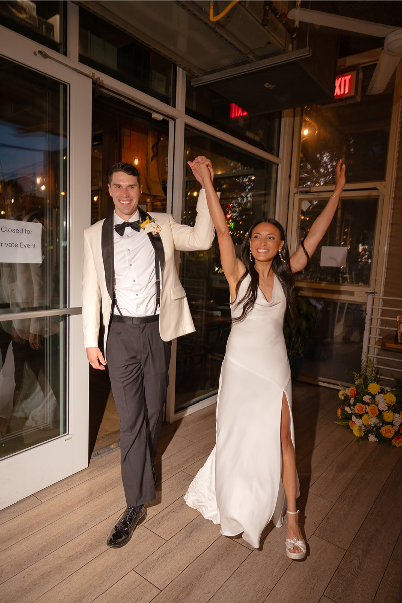 A couple in formal attire, holding hands and smiling, walk into a venue decorated with flowers; a "Closed for Private Event" sign is visible on the door.